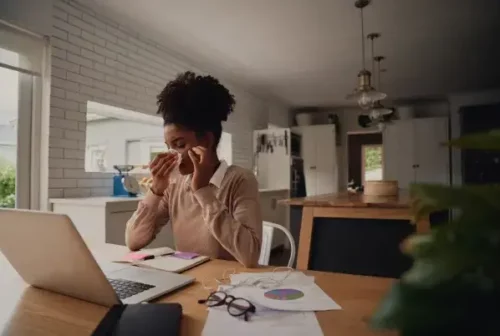 Woman Sneezing In Her Home Office While Working