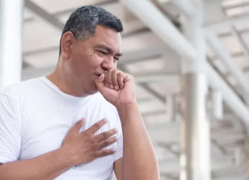 Man having a hard cough outside in the open holding his chest