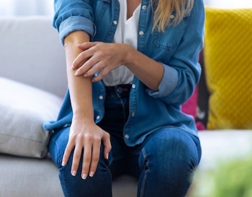 Woman sitting on the bed and touching her hand after drug allergy