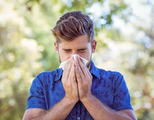 Man blowing his nose outside - rhinitis symptoms