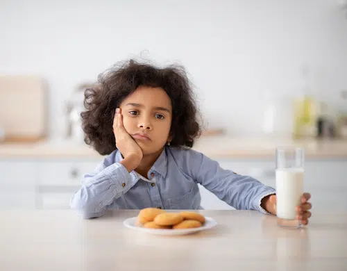 Portrait Of Sad Little Black Girl Holding Glass Of Milk