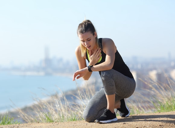 Tired runner controlling pulsations checking smartwatch