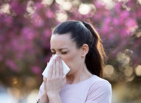 Woman blowing nose because of spring pollen allergy