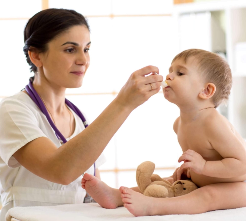 Female physician giving medicine to a baby boy with a spoon