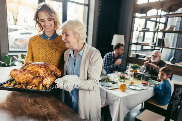 Senior mother and daughter with thanksgiving turkey for family dinner at home