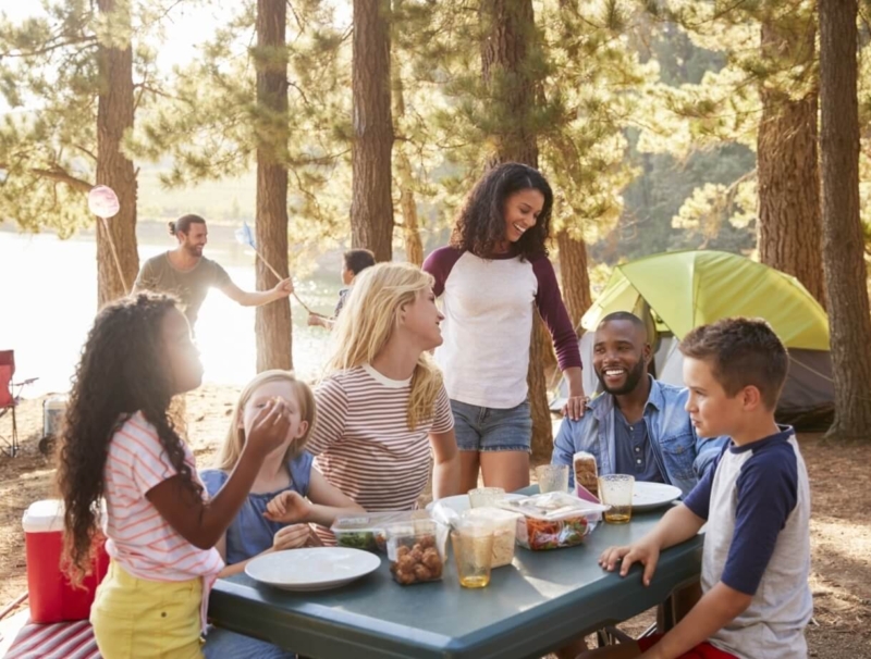 Family With Friends Camp By Lake On Hiking Adventure In Forest