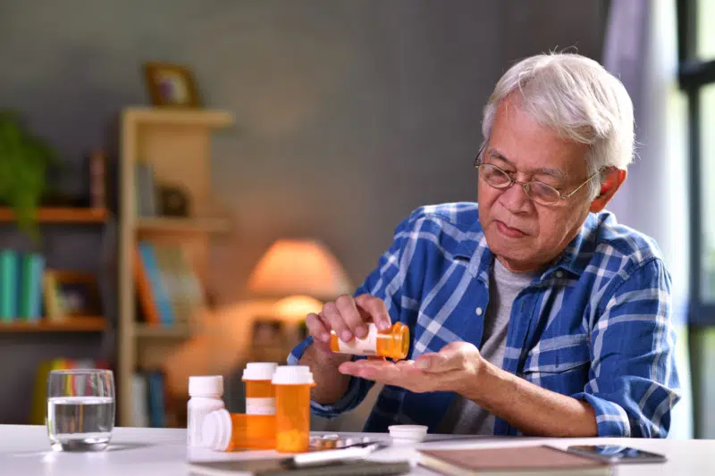 Asian senior man taking medicine at home