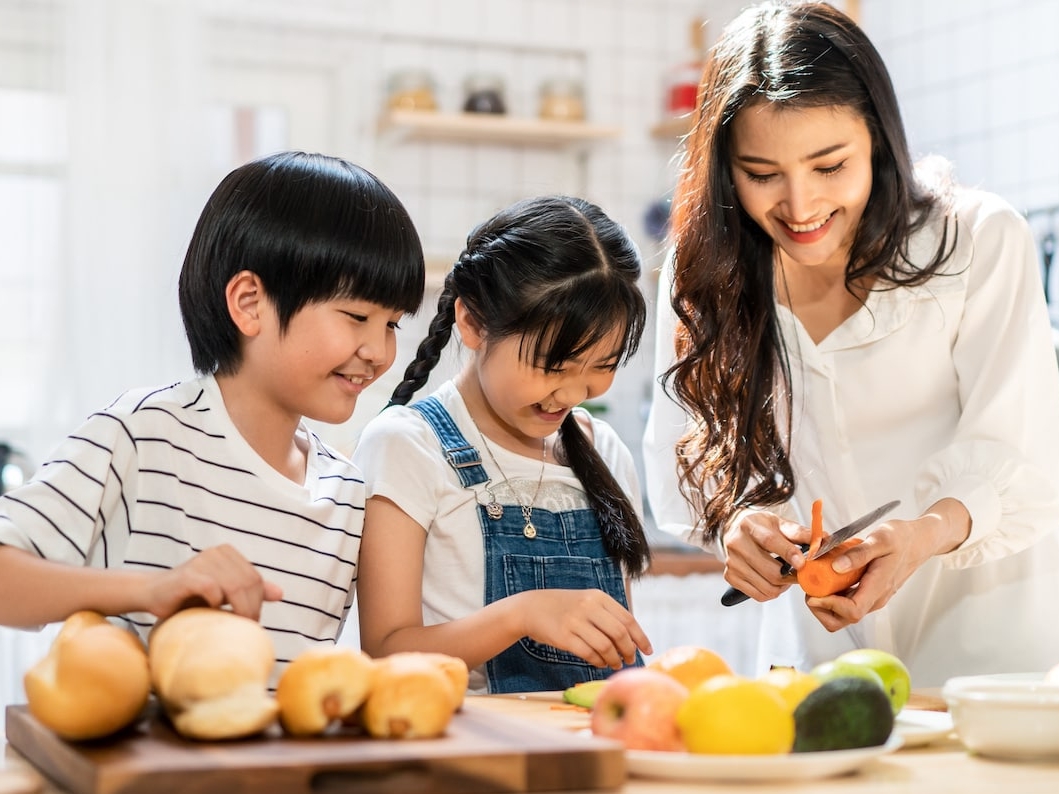 Children and mother preparing cooking fruits and vegetables to avoid oral allergy syndrome symptoms naturally.