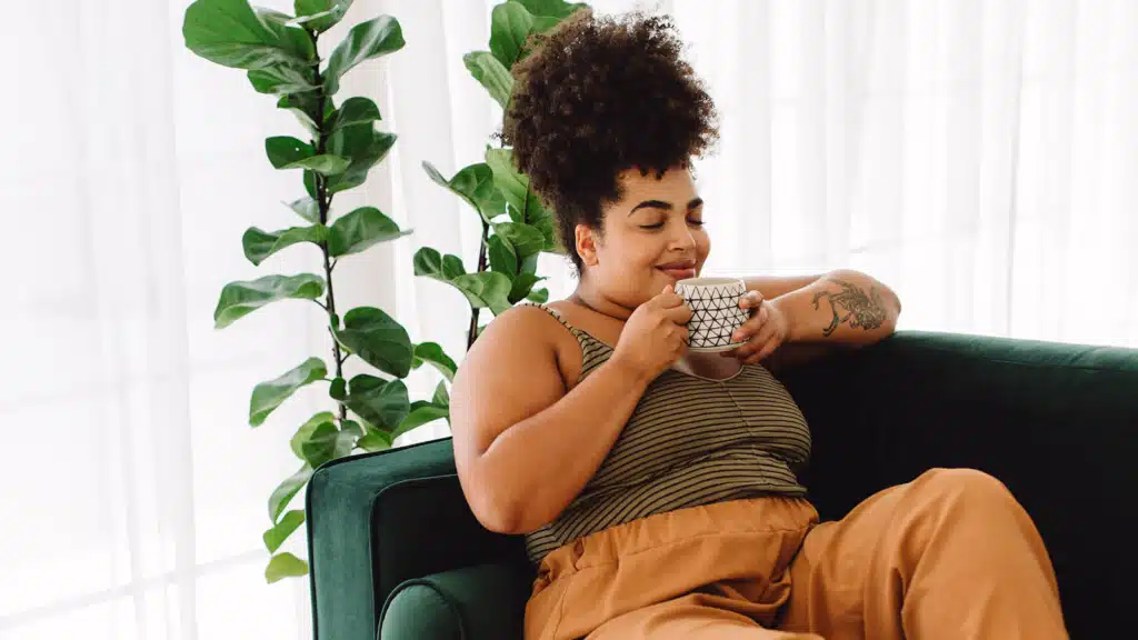 Woman sitting on a couch enjoying a cup of coffee