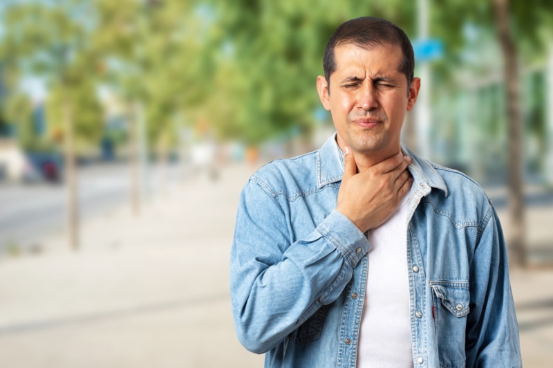 man outside feeling bad with sore throat