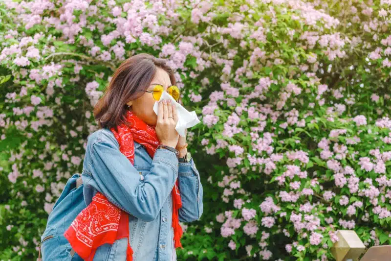 Young Asian woman sneezes and blowing her nose