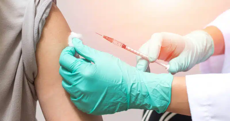 Hands of doctor or nurse in medical gloves injecting an allergy shot to a man patient