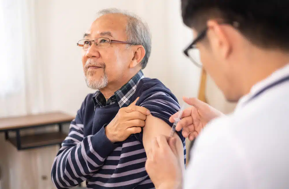 Asian doctor administering biologics for asthma injection on an elder patient with severe asthma symptoms