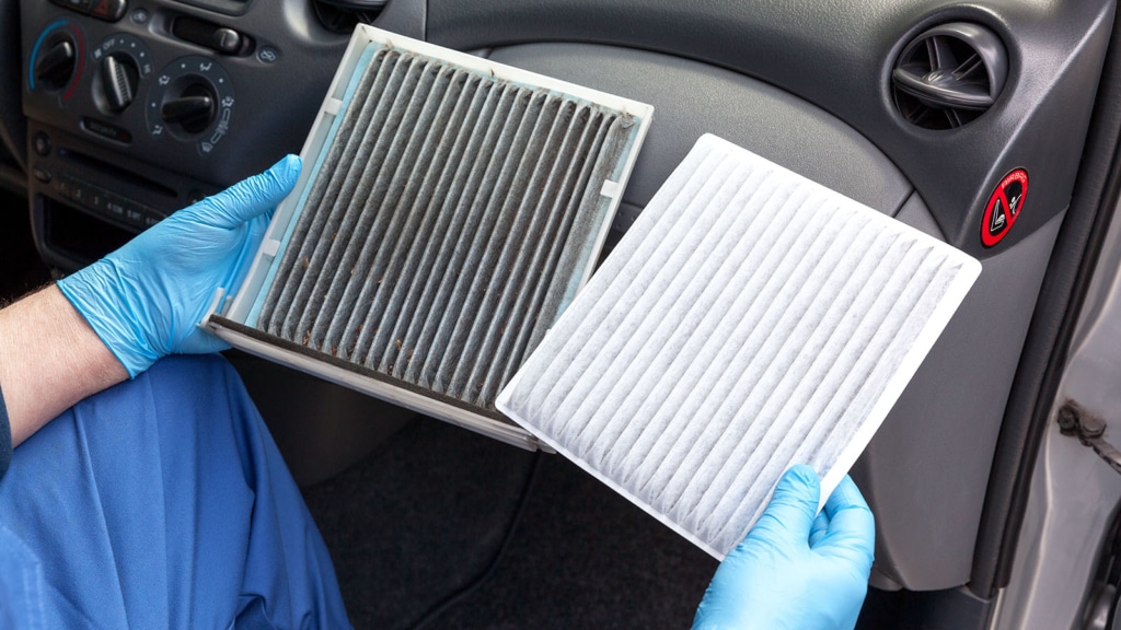 Man in gloves showing a dirty car air filter