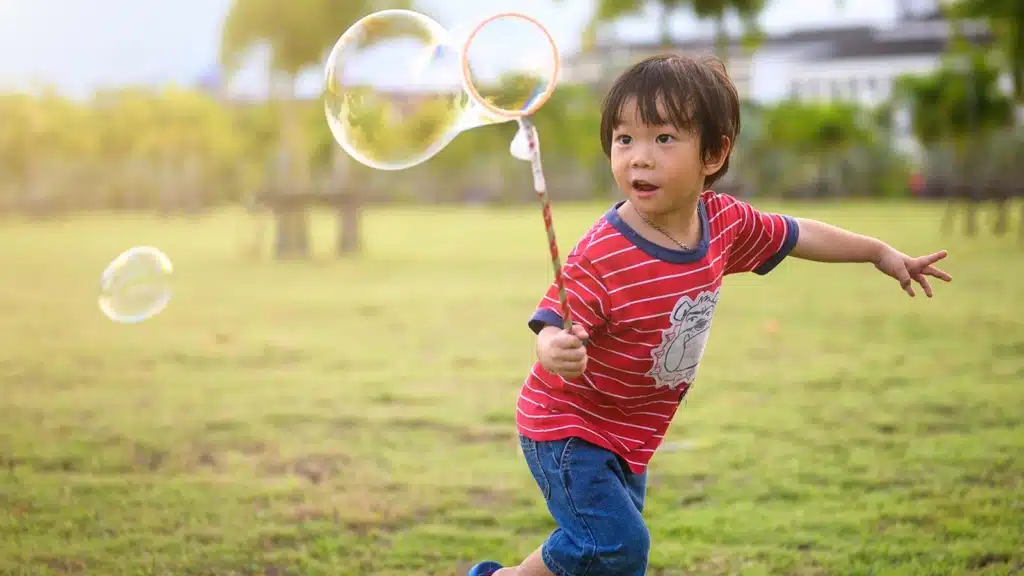 Little boy making bubbles and playing outside and enjoying the outdoors