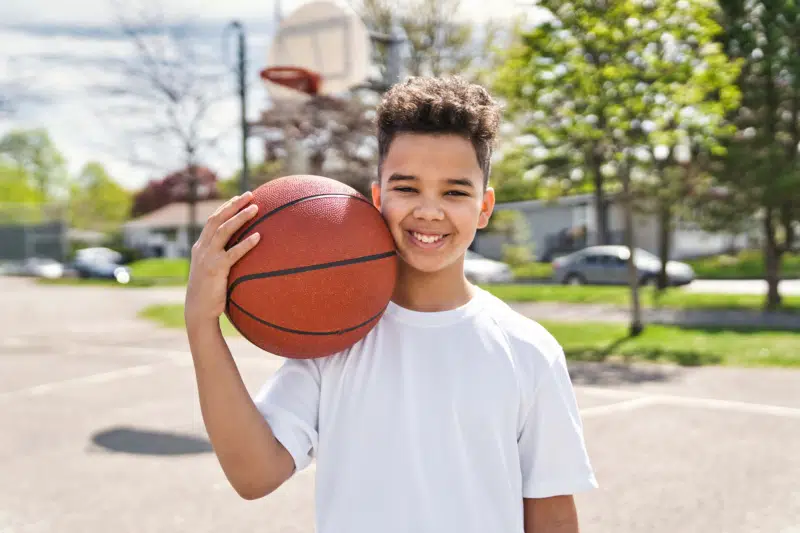 Little boy, smiling, in a basketball court holding a basket ball