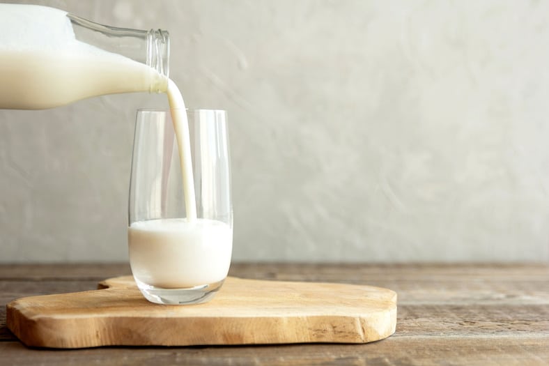 Kefir, milk or Turkish Ayran drink are poured into a glass cu