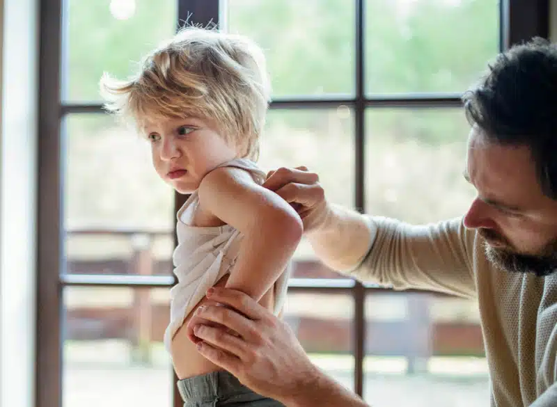 Allergist examining a little boy's back for eczema