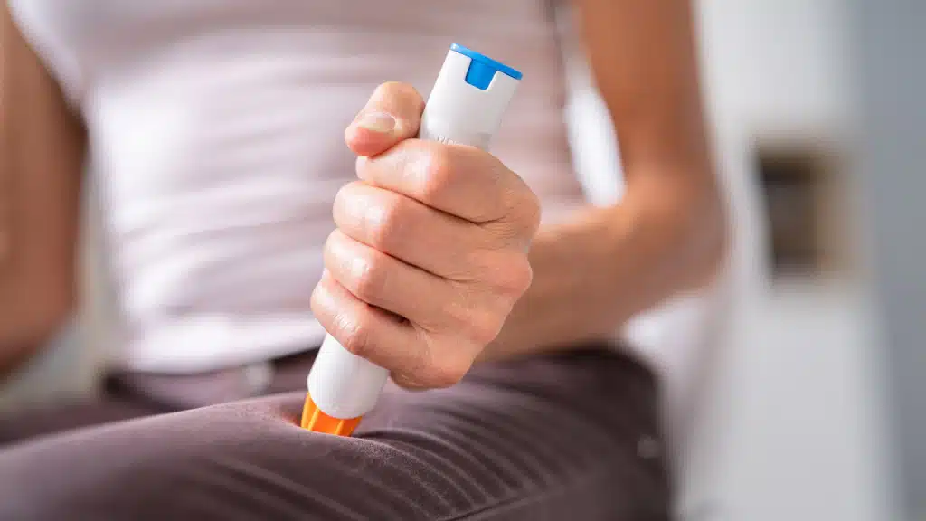 Woman injecting herself on the leg with an epipen