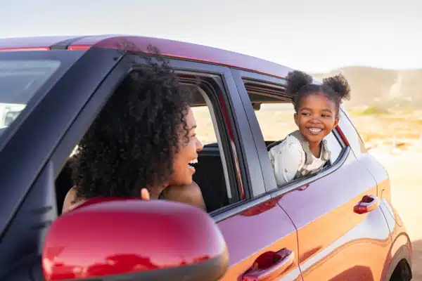 Mother and black daughter peeping outside car, daughter is on the back seat