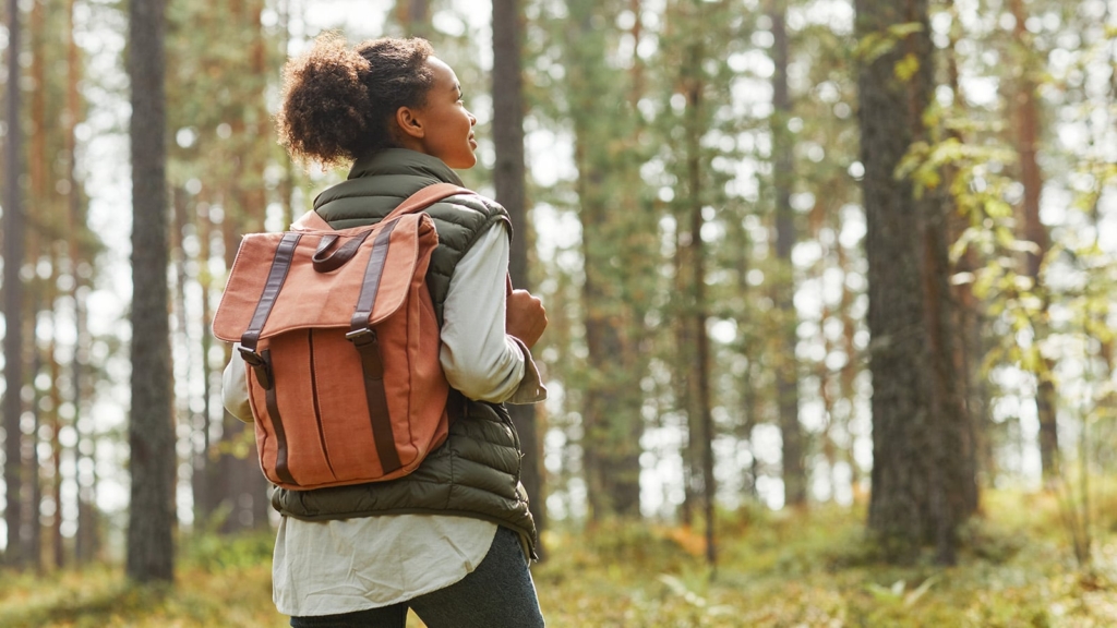 Young woman on a hiking trip with a backpack in the woods