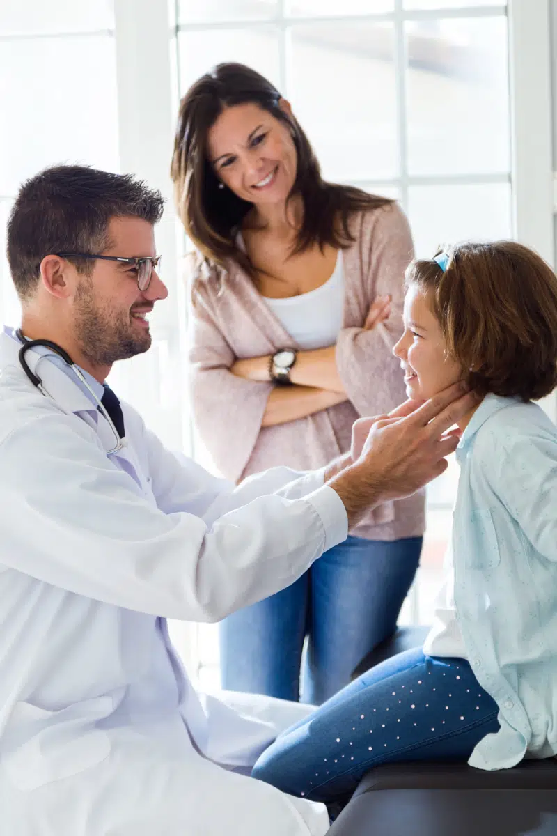 Mother with her daughter having throat examination by pediatrician in the office.