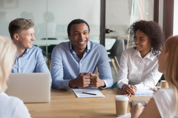 Smiling multiracial colleagues negotiate cooperating at meeting