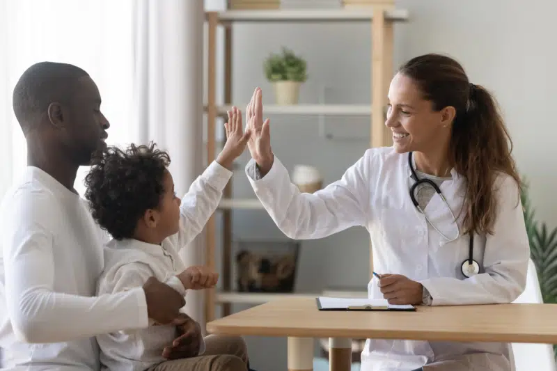 Happy african child boy give high five to female doctor