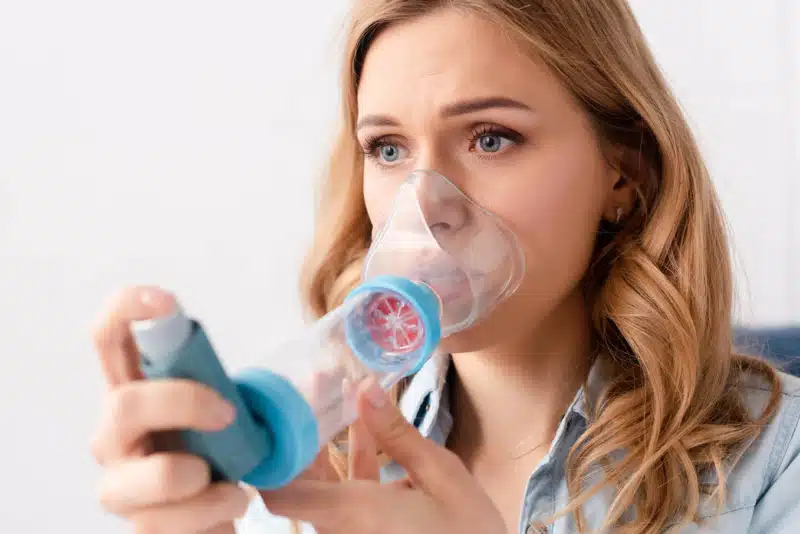 Asthmatic woman using inhaler with spacer