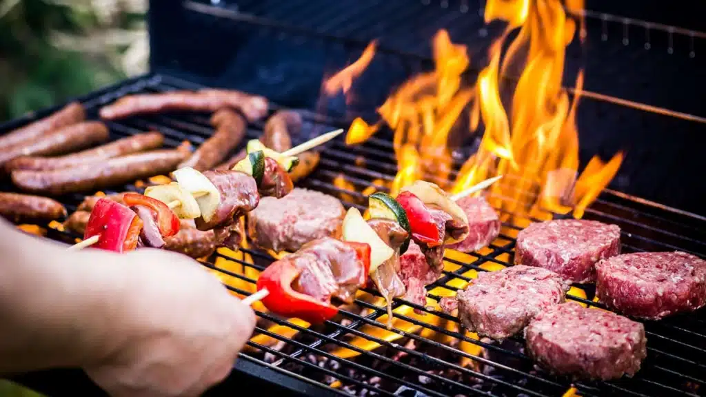 Variety of meats being grilled, flames of the grill on the back