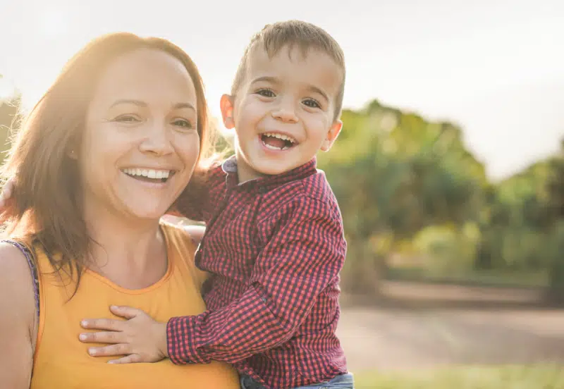 Happy latin mother holding son in her arms and laughing