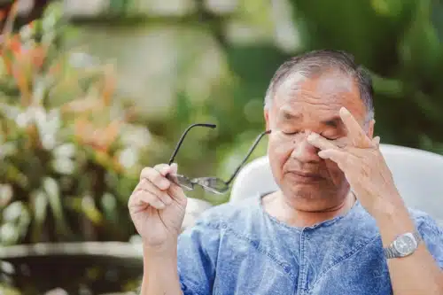An elderly man rubbing his eyes due to excessive use of his eyes, causing itching and irritation.