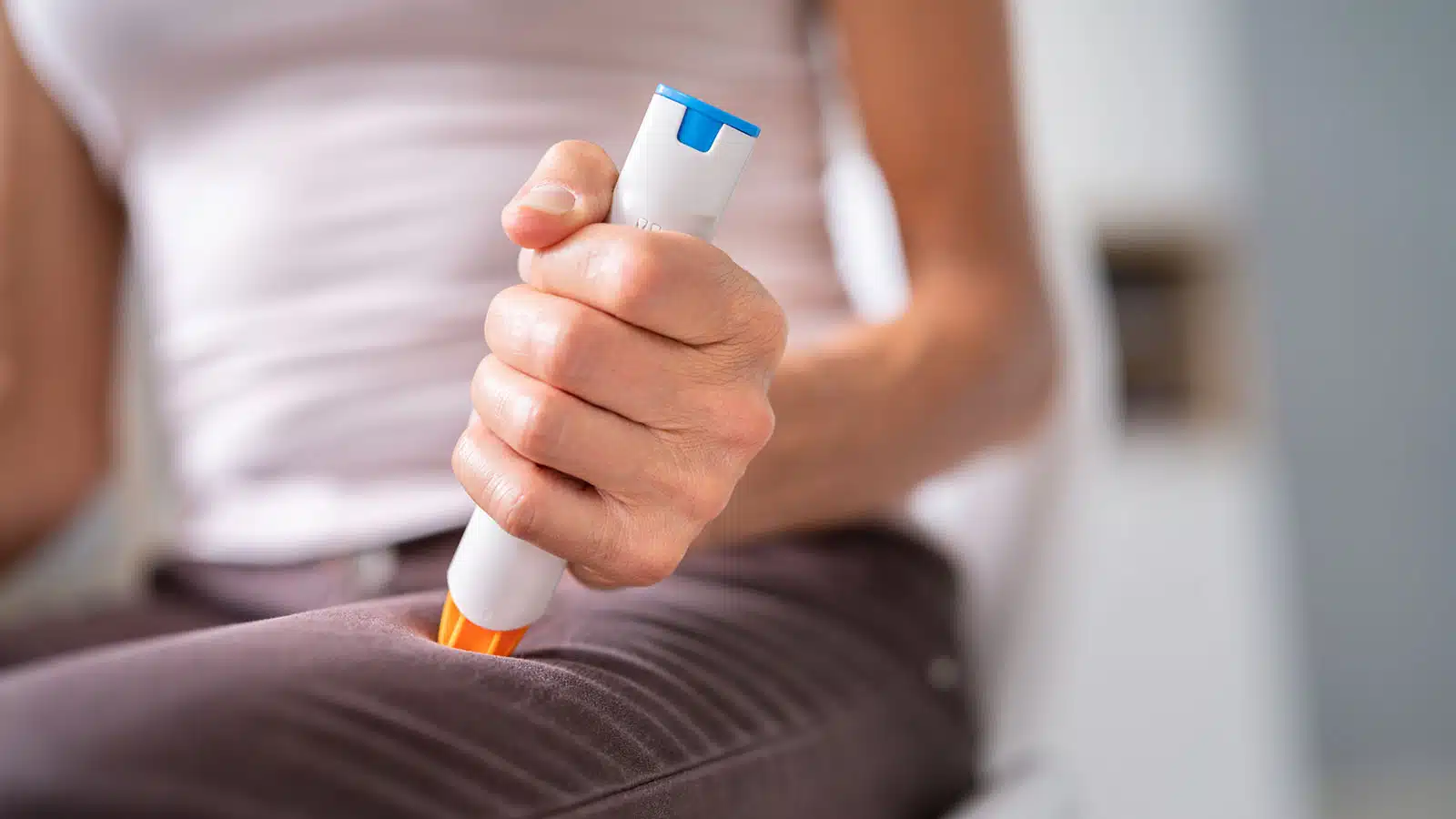 Woman injecting herself epinephrine  with an EpiPen