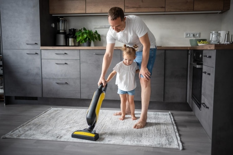 Father and daughter having fun with vacuum cleaner