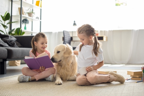 little sisters with books and golden retriever dog