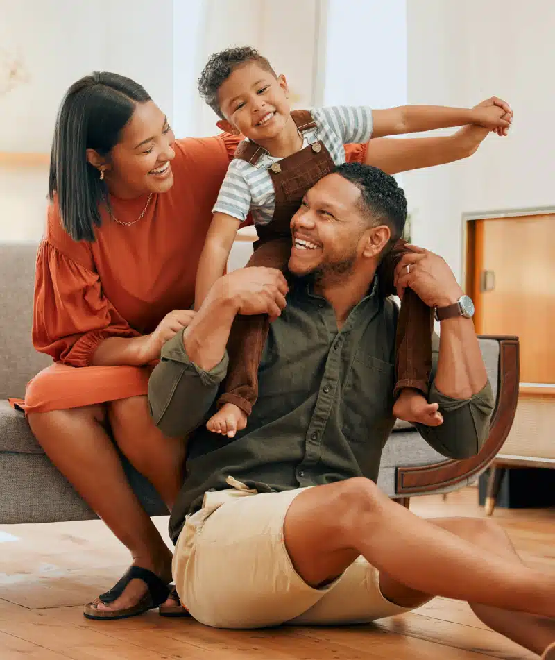 A happy mixed race family of three relaxing in the lounge and being playful together.