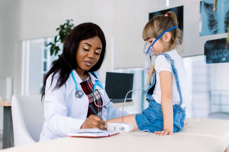 Medical doctor applying medicine inhalation treatment on a little girl with severe asthma.