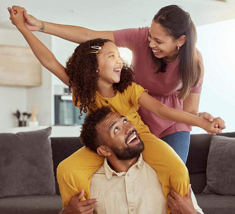 Happy family celebrating, a girl is on her father's shoulders and her mom is grabbing the girl