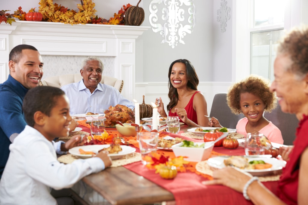 Family gathered on a table eating dinner celebrating Thanksgiving 