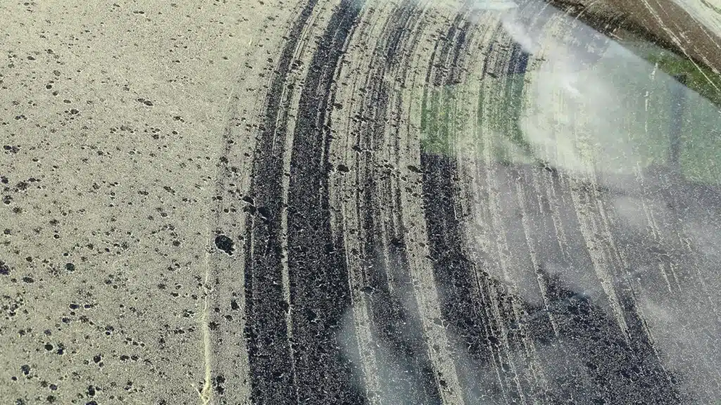 Car windshield covered in yellow pollen with marks of wipers trying to remove the pollen