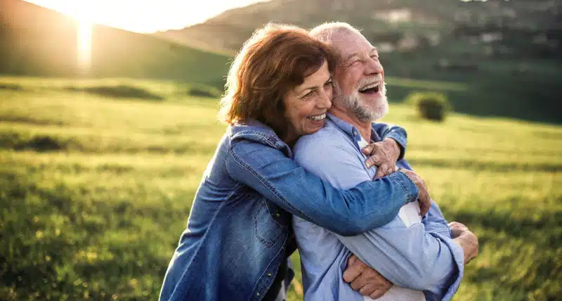 Side view of senior couple hugging outside in spring nature at sunset