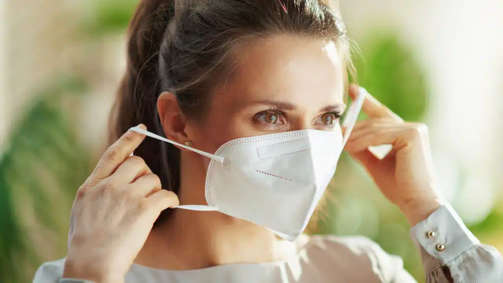 Young woman placing a white face mask