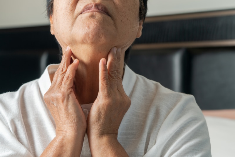 Senior adult woman touching the neck feeling unwell coughing with sore throat pain